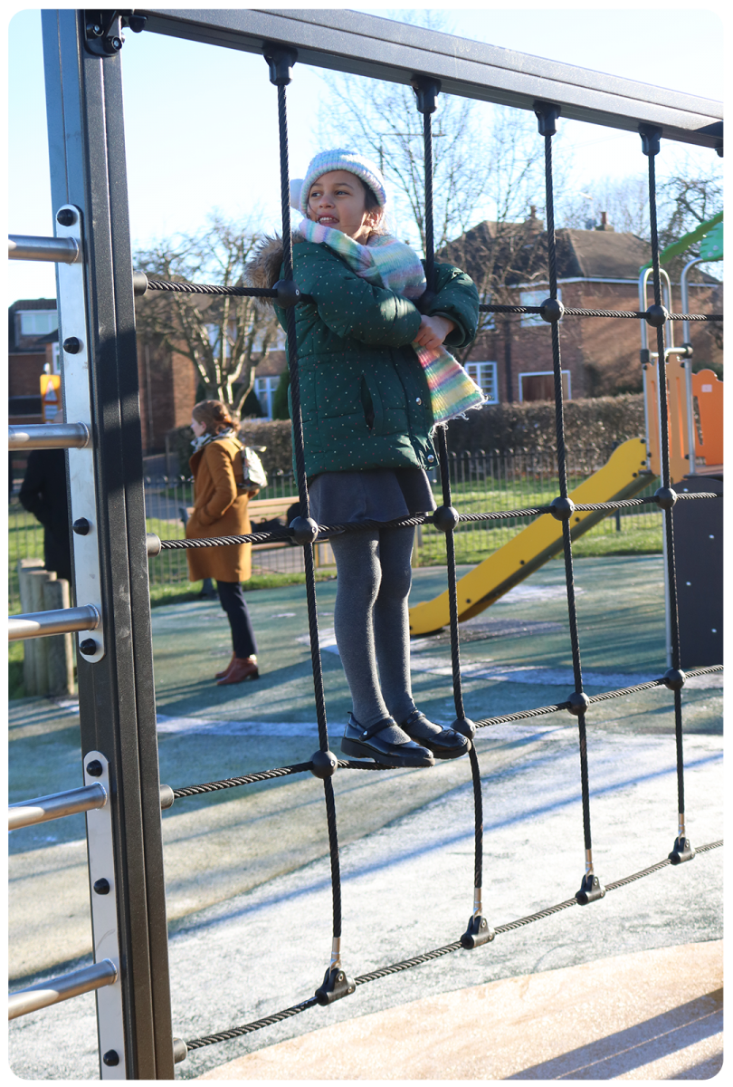 A young girl climbing a climbing net on one of our climbing and balancing units.